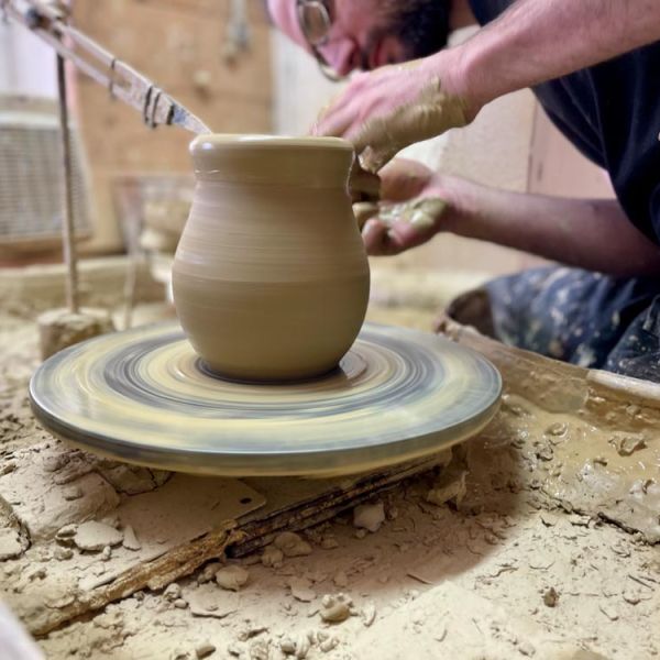 village potter throwing a pot on potter's wheel