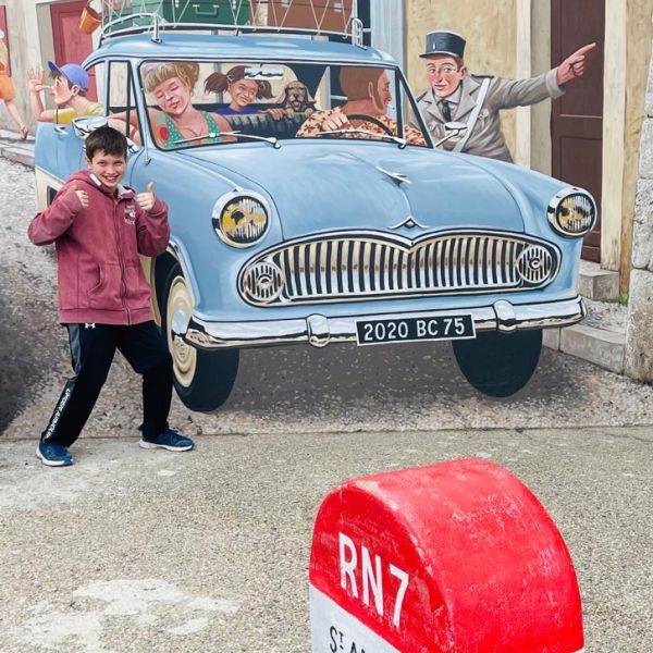 boy poses in front of trompe l'oeil mural in French village of St. Andiol